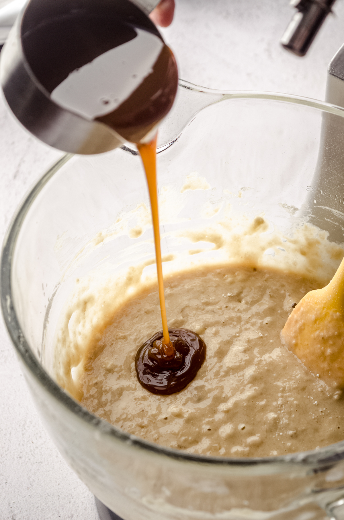 Someone is pouring salted caramel sauce into banana bread batter.