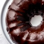 A photo of an aerial photo of a chocolate Bundt cake with chocolate ganache on a plate.
