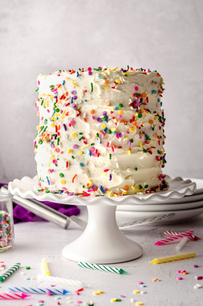 A rainbow layer cake on a cake stand.