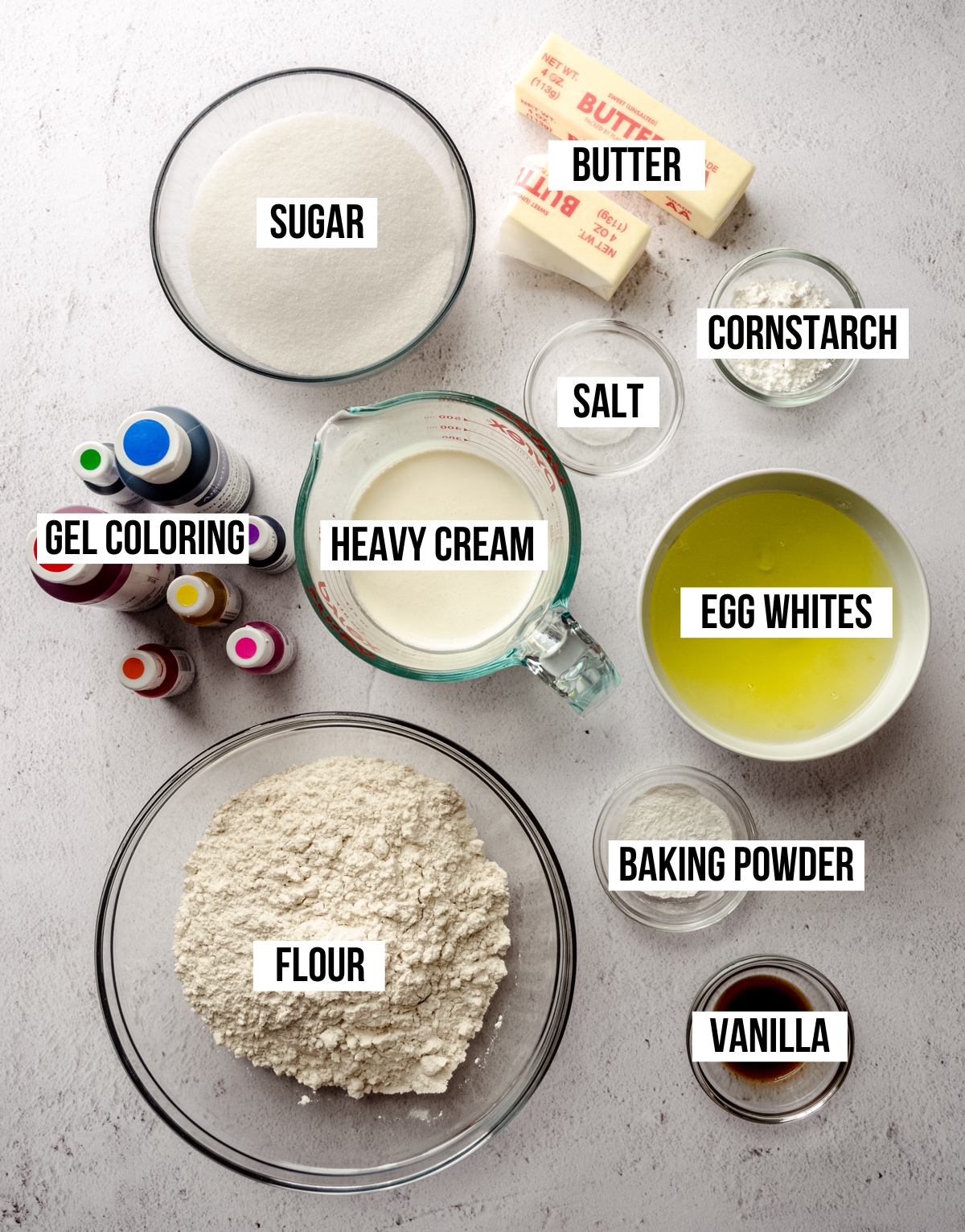 Aerial photo of ingredients for rainbow layer cake with text overlay labeling each ingredient.