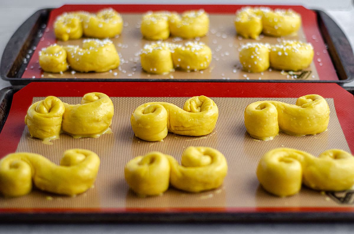 shaped saffron buns on a baking sheet