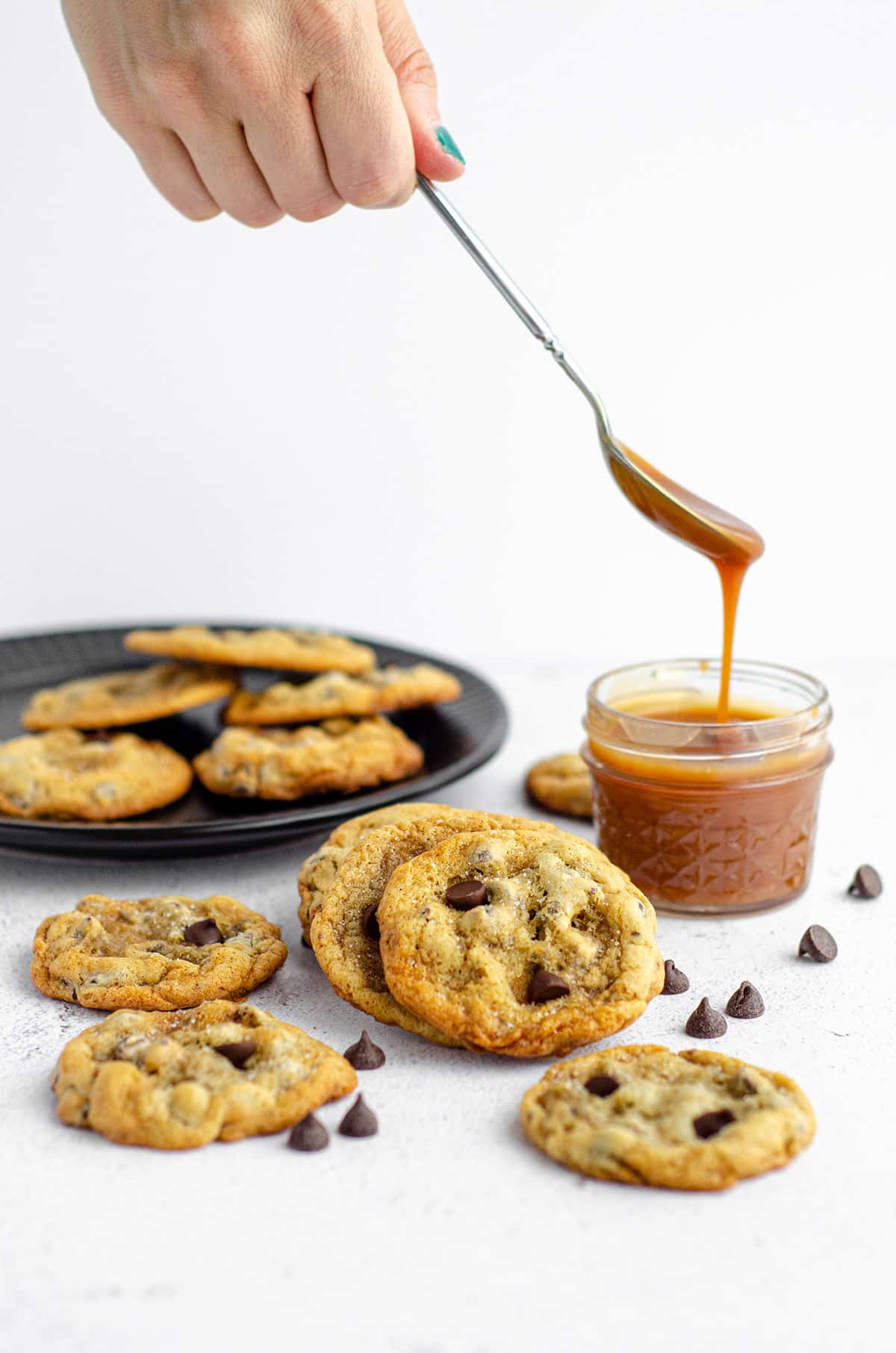 salted caramel chocolate chip cookies with a jar of salted caramel sauce in the background