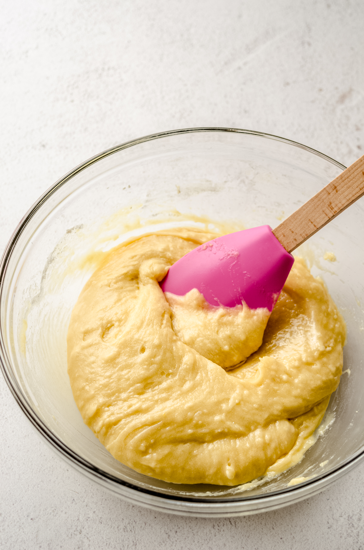 A glass bowl full of sugar cookie dough with a pink spatula in it.