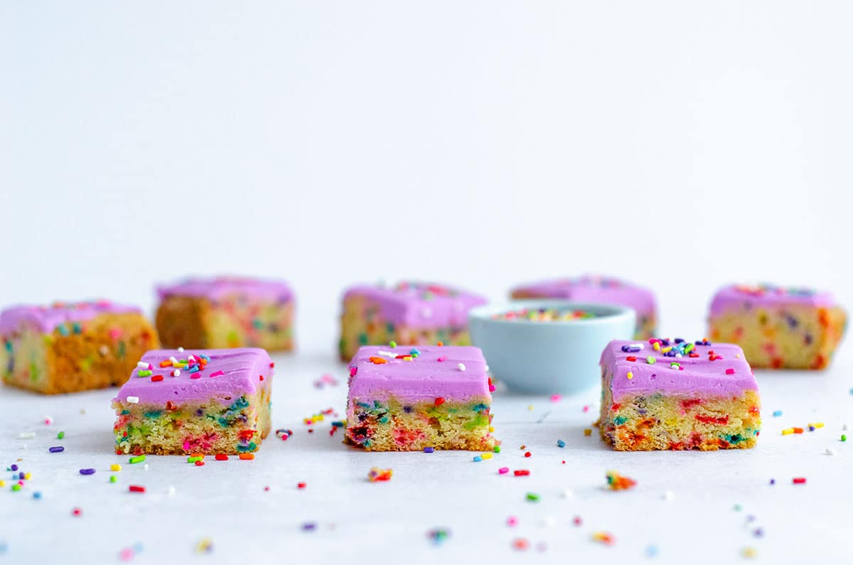 sugar cookie bars on a surface with sprinkles all around