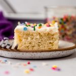 A slice of white sheet cake on a plate with a fork.