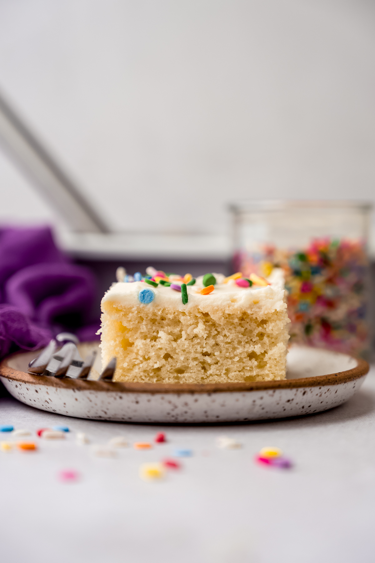 A slice of white sheet cake on a plate with a fork.