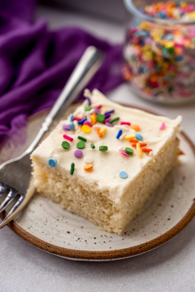 A slice of white sheet cake on a plate with a fork.