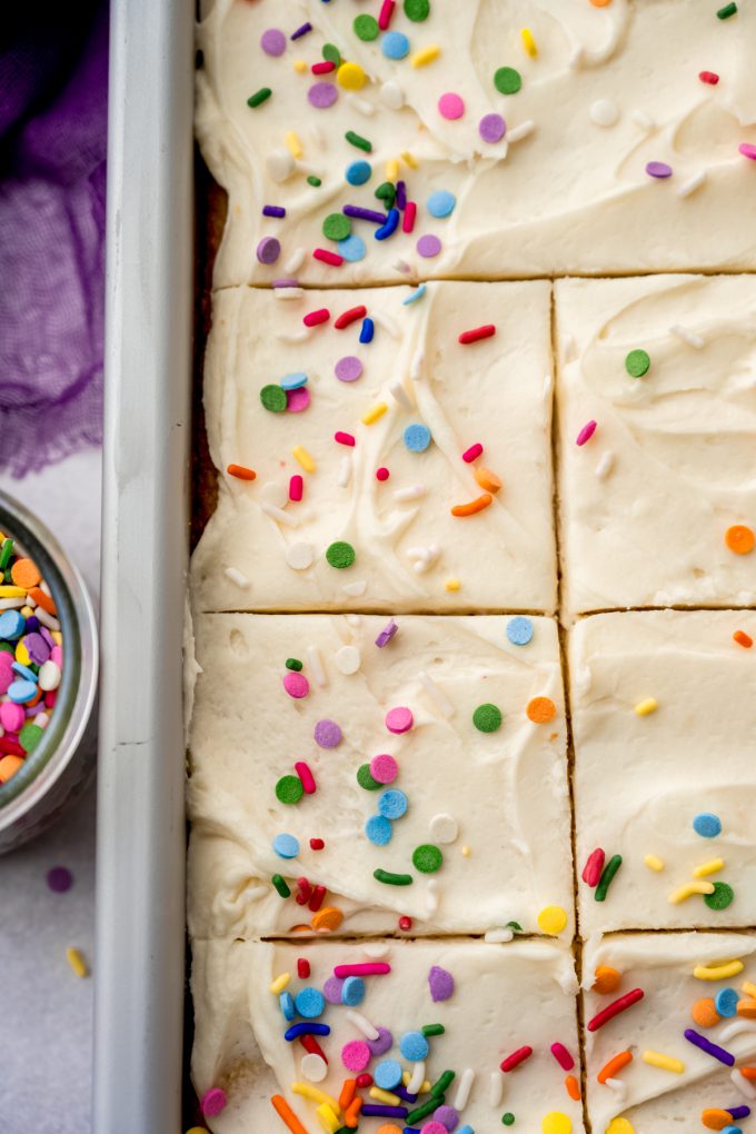 Aerial photo of a white sheet cake in a pan and it has been sliced.