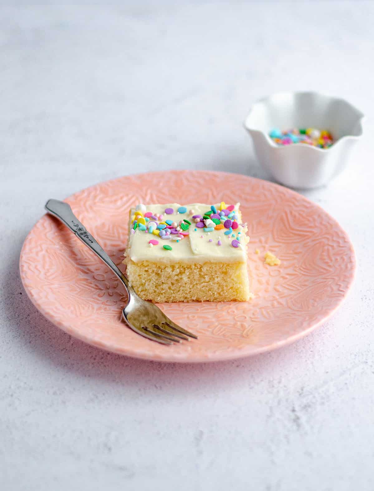 slice of white sheet cake on a pink plate