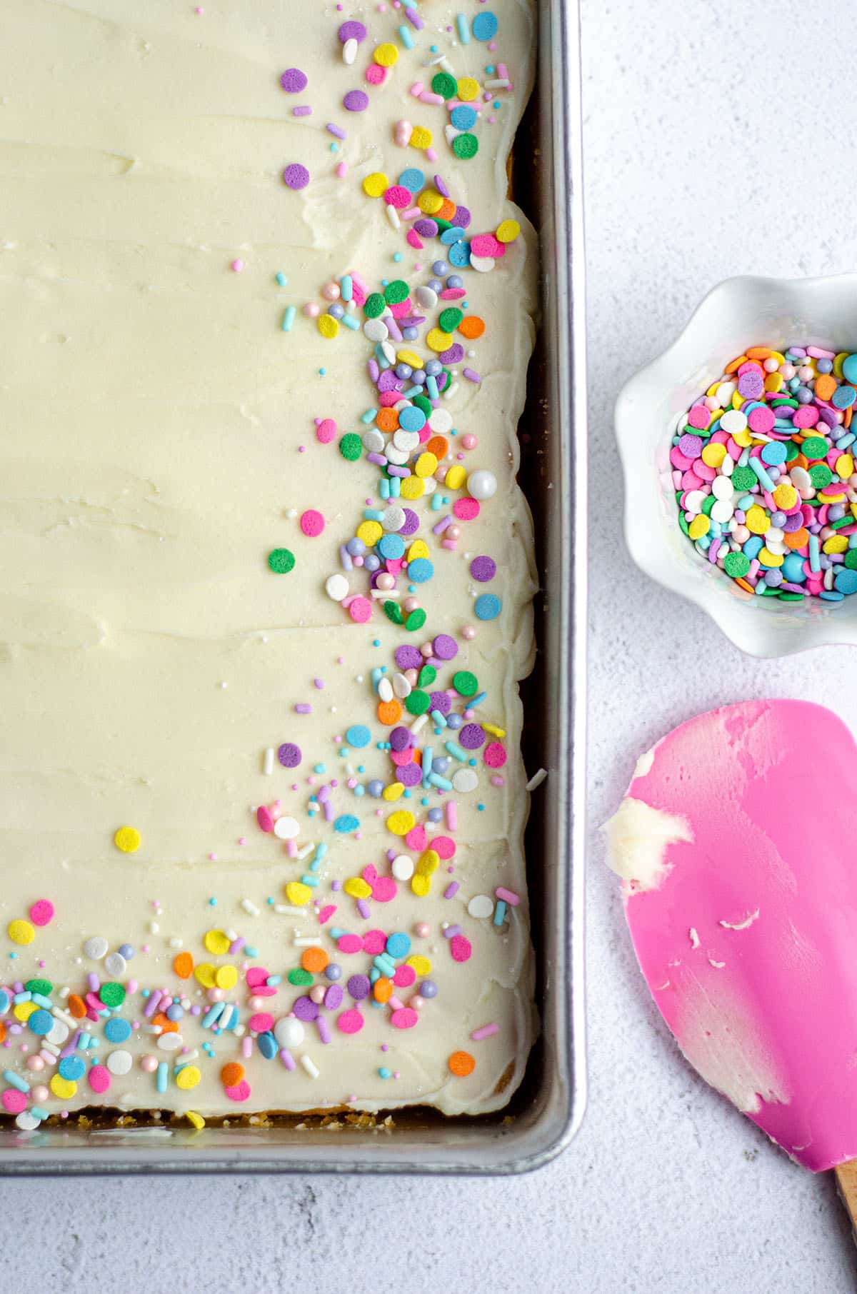 white sheet cake in a pan with colorful sprinkles