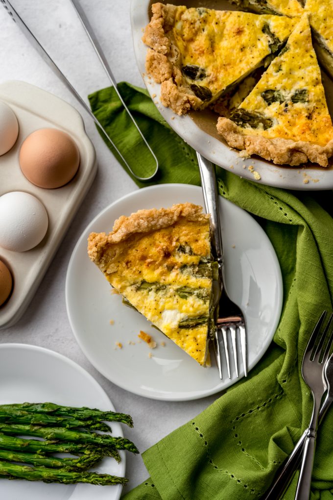 Aerial photo of a slice of asparagus quiche on a plate with a fork.