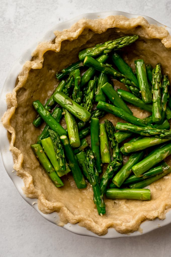 Aerial photo of chopped asparagus stalks in a pie crust to make quiche.
