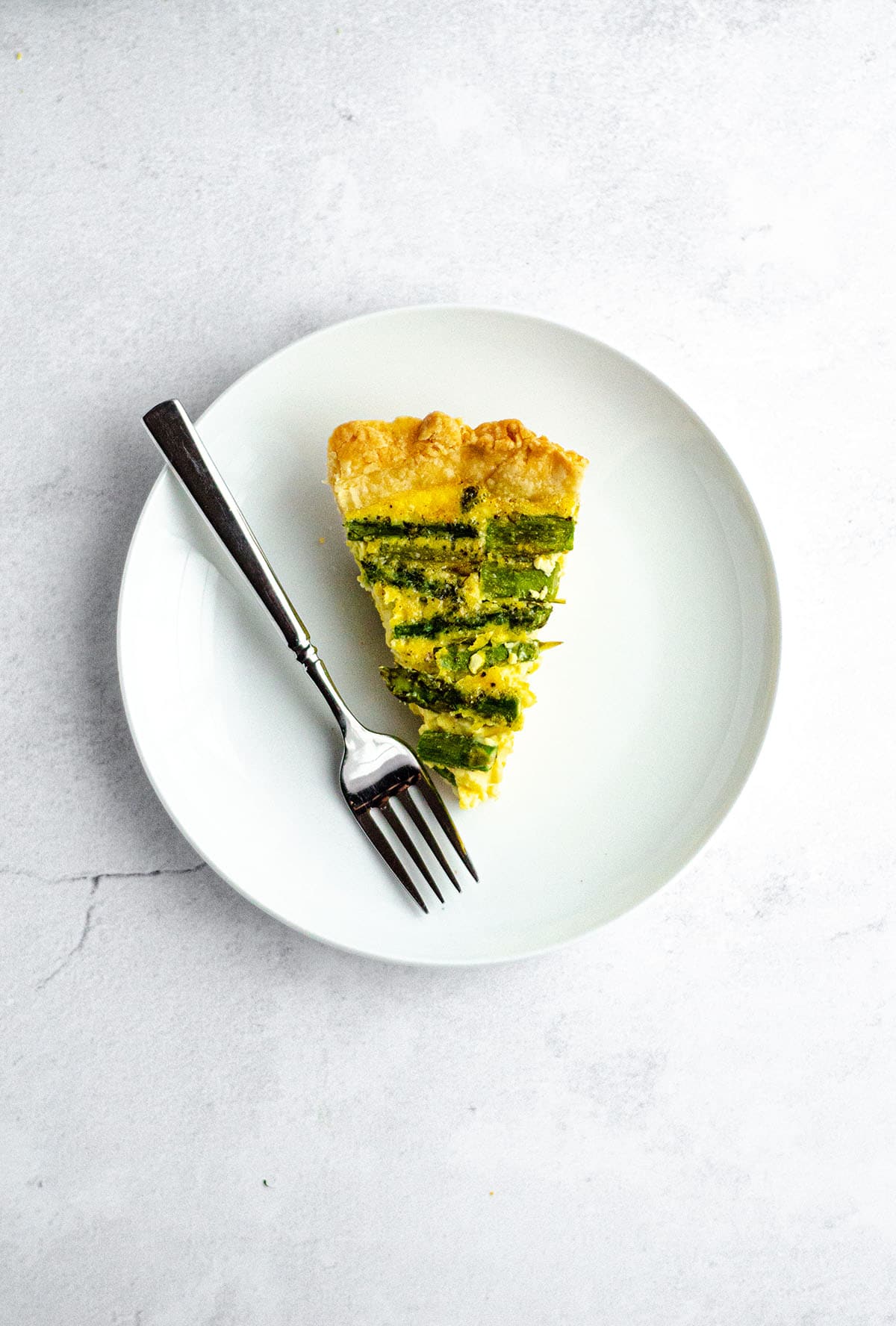 aerial photo of a slice of asparagus quiche on a plate with a fork