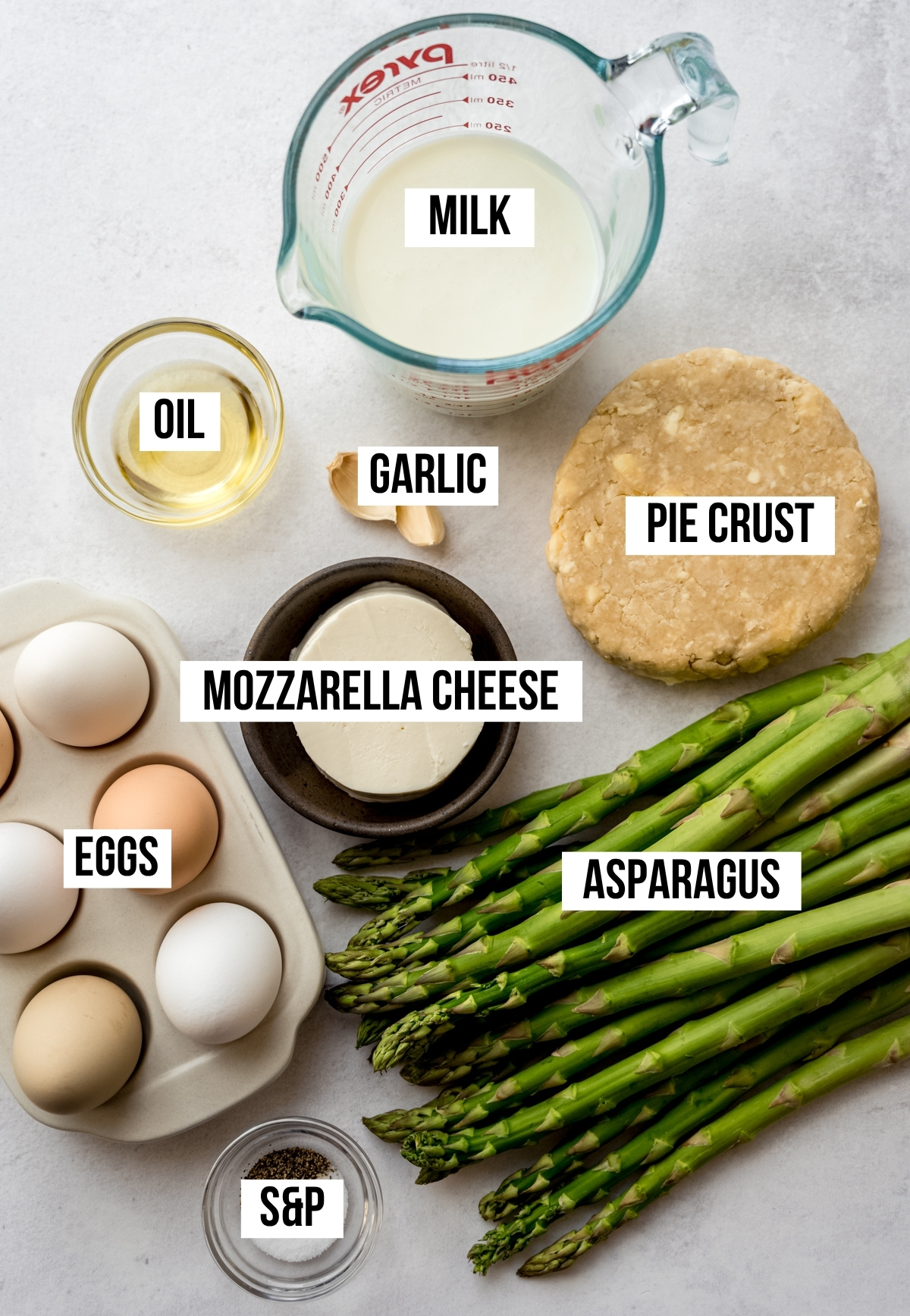 Aerial photo of ingredients to make asparagus quiche with text overlay labeling each ingredient.