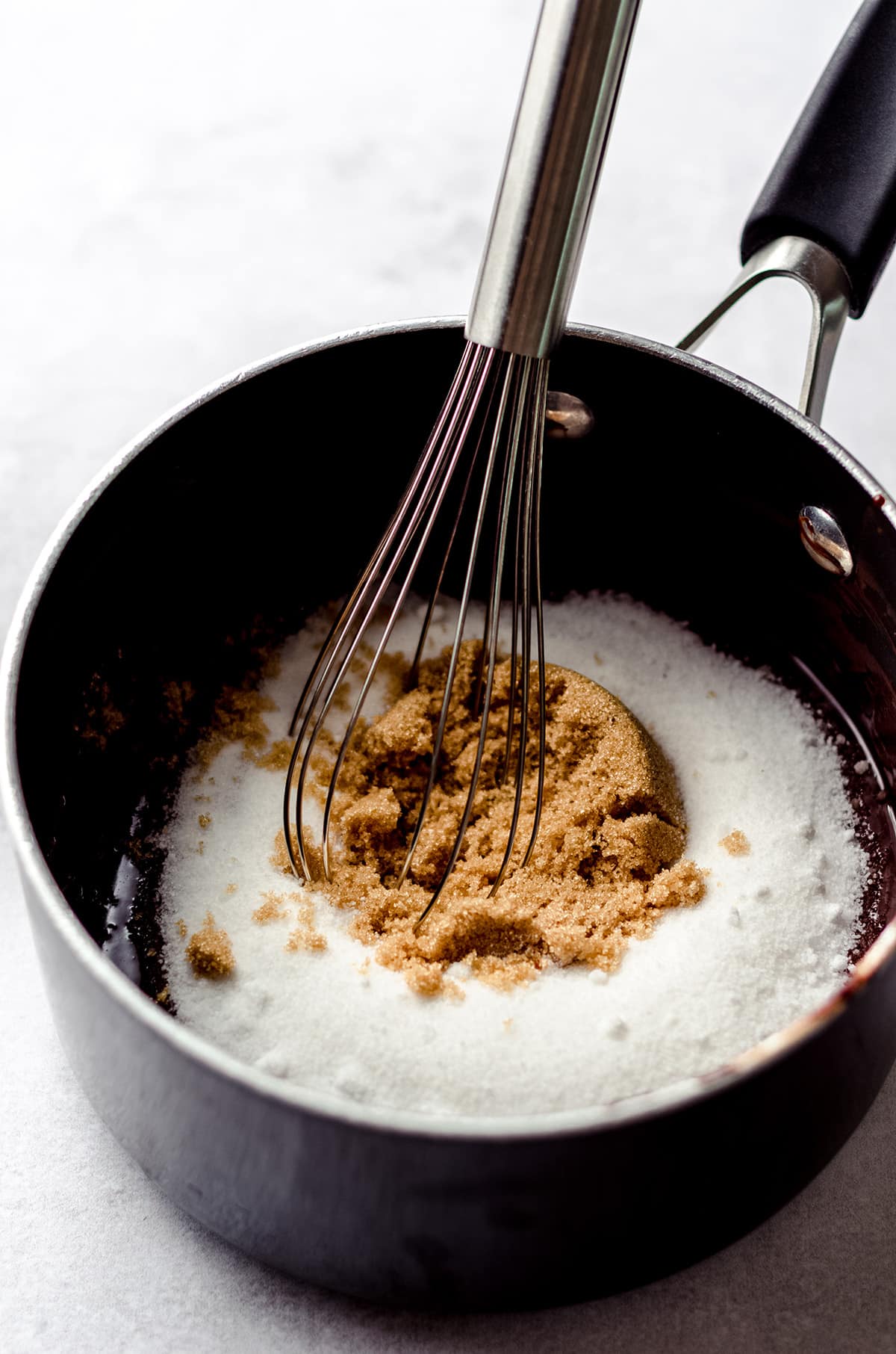 whisking sugar into brownie batter in a saucepan