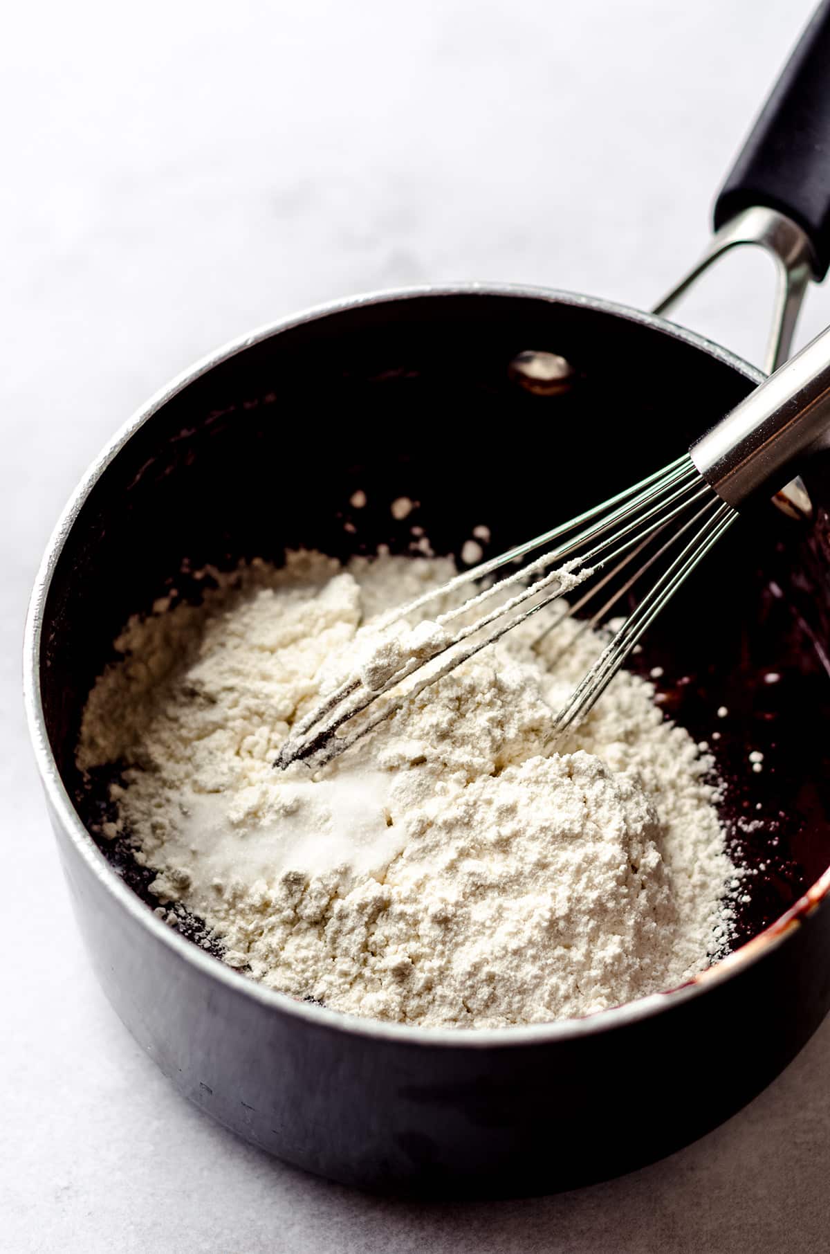 whisking flour into brownie batter in a saucepan