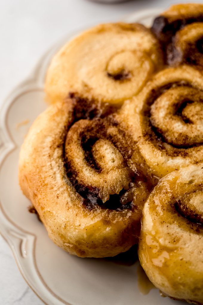 Caramel cinnamon rolls on a plate before getting a topping of cream cheese frosting.