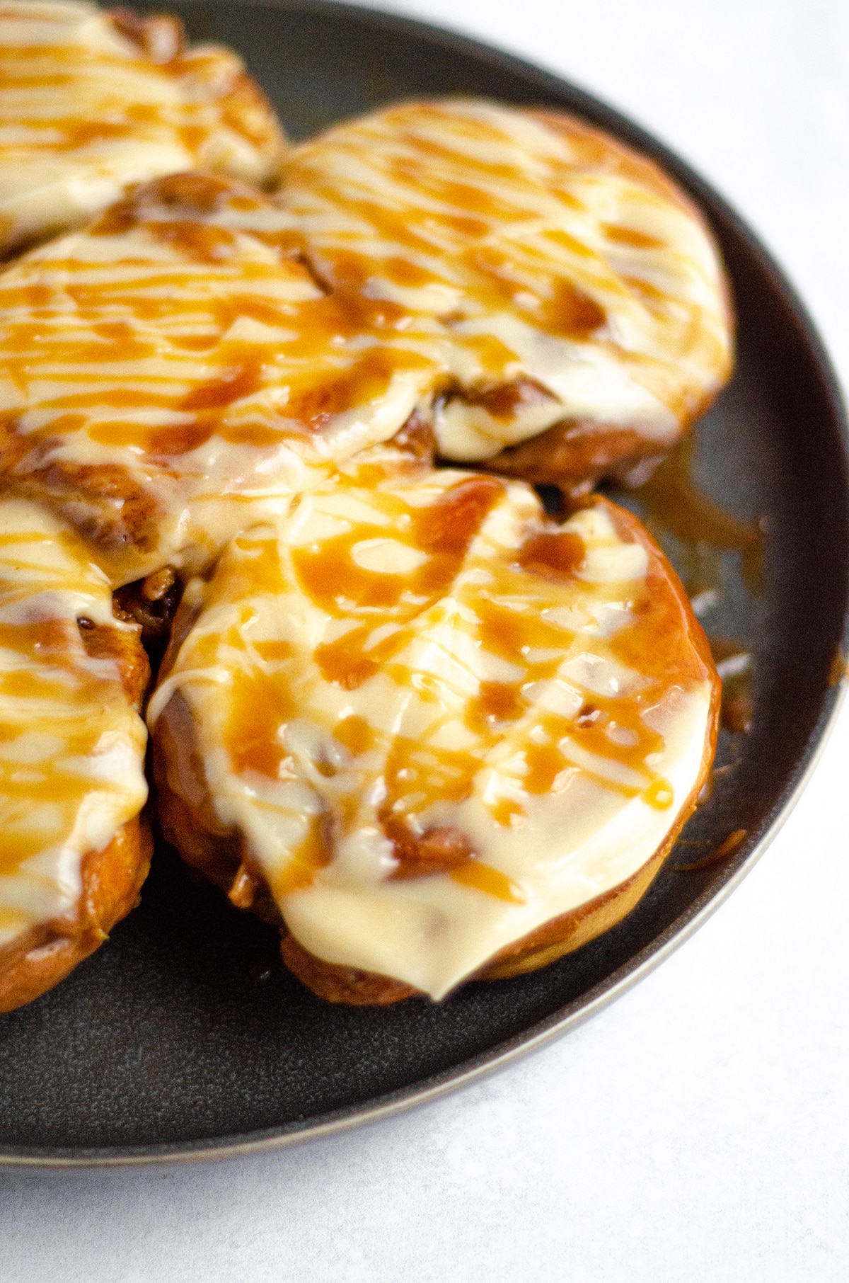 caramel rolls with caramel cream cheese frosting on a plate