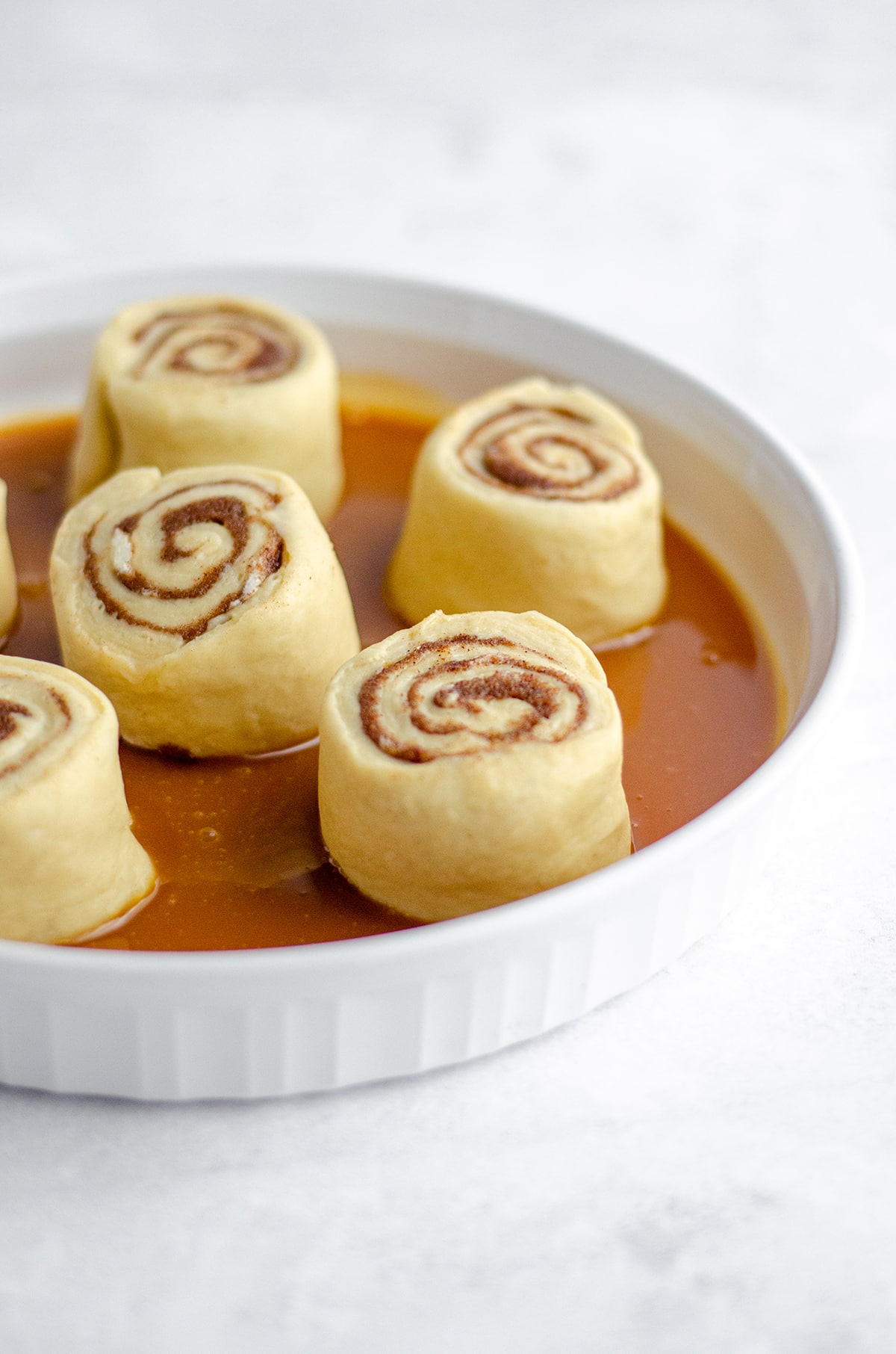 caramel roll dough in a plate with caramel sauce on the bottom ready to rise