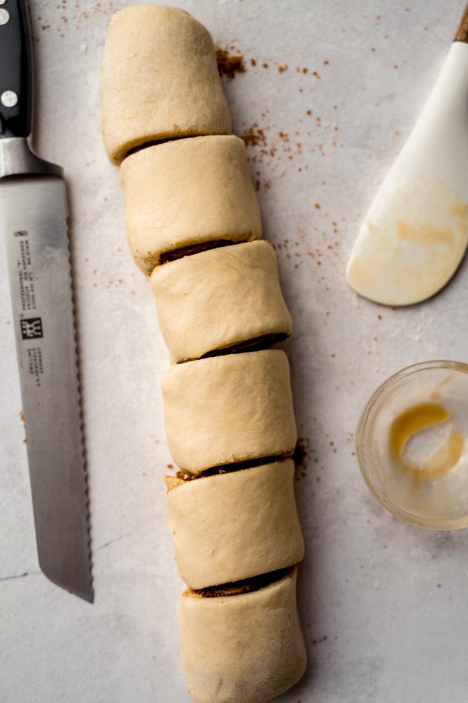 Aerial photo of a log of cinnamon roll dough cut into slices.