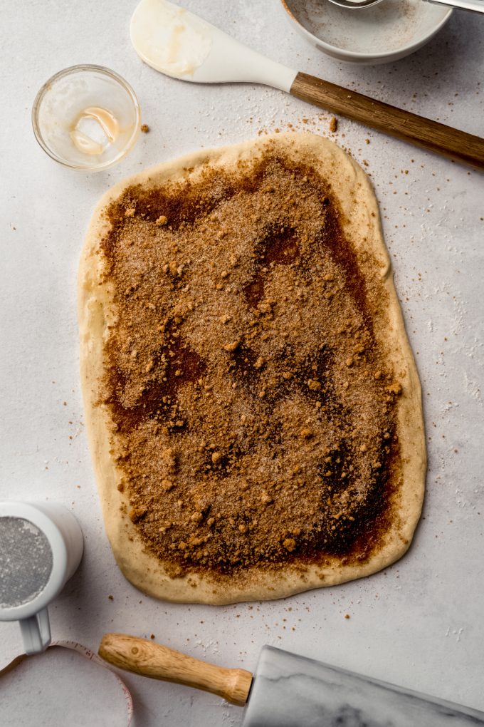 Aerial photo of a rectangle of cinnamon roll dough with filling spread onto it before it gets rolled up.