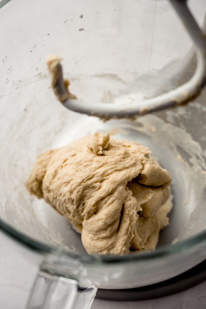 The bowl of a stand mixer with a bolus of yeast dough in it.