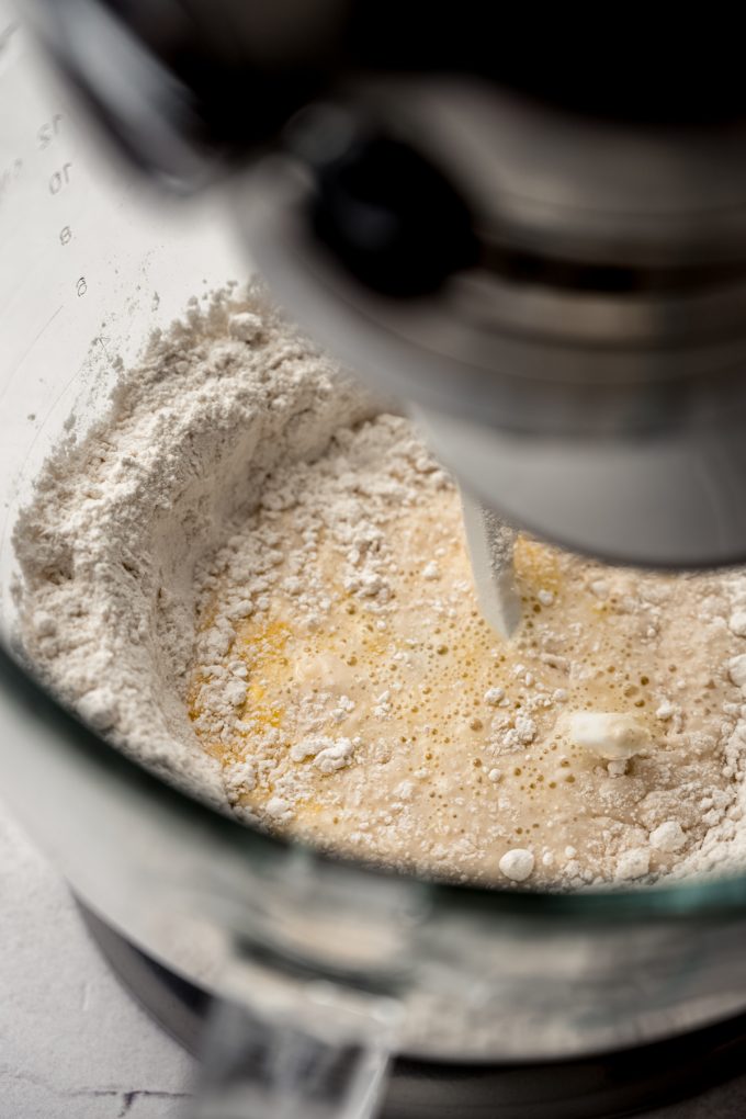 The bowl of a stand mixer with the start of yeast dough in it.