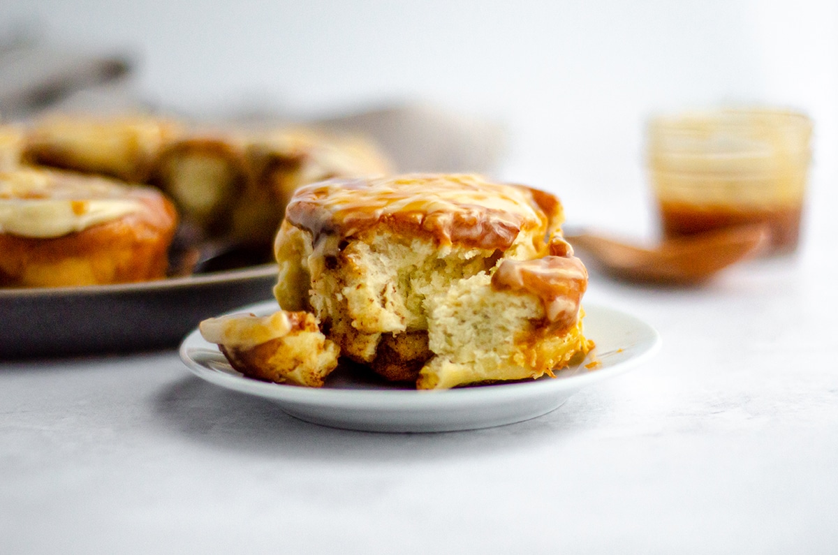 caramel roll with caramel cream cheese frosting on a white plate