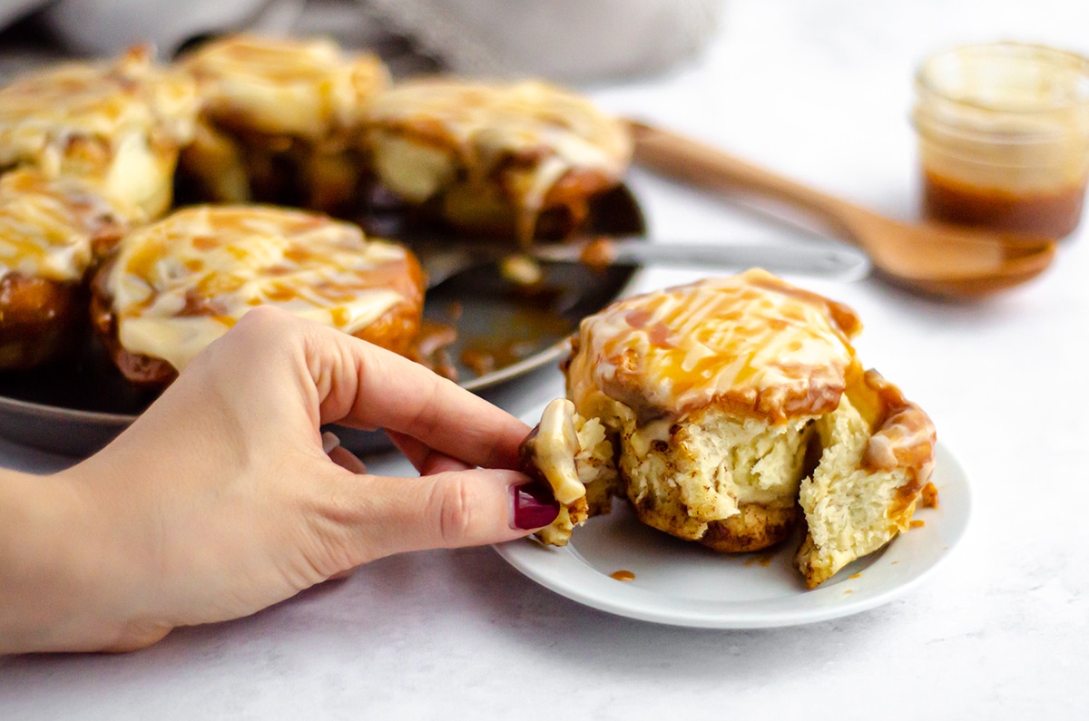 fingers pulling apart a caramel roll 