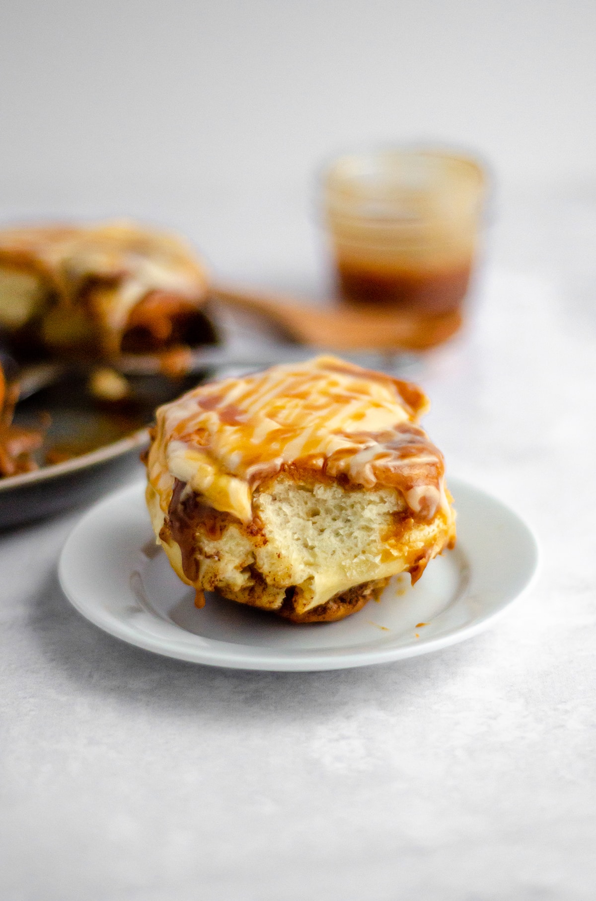 caramel roll with caramel cream cheese frosting on a white plate