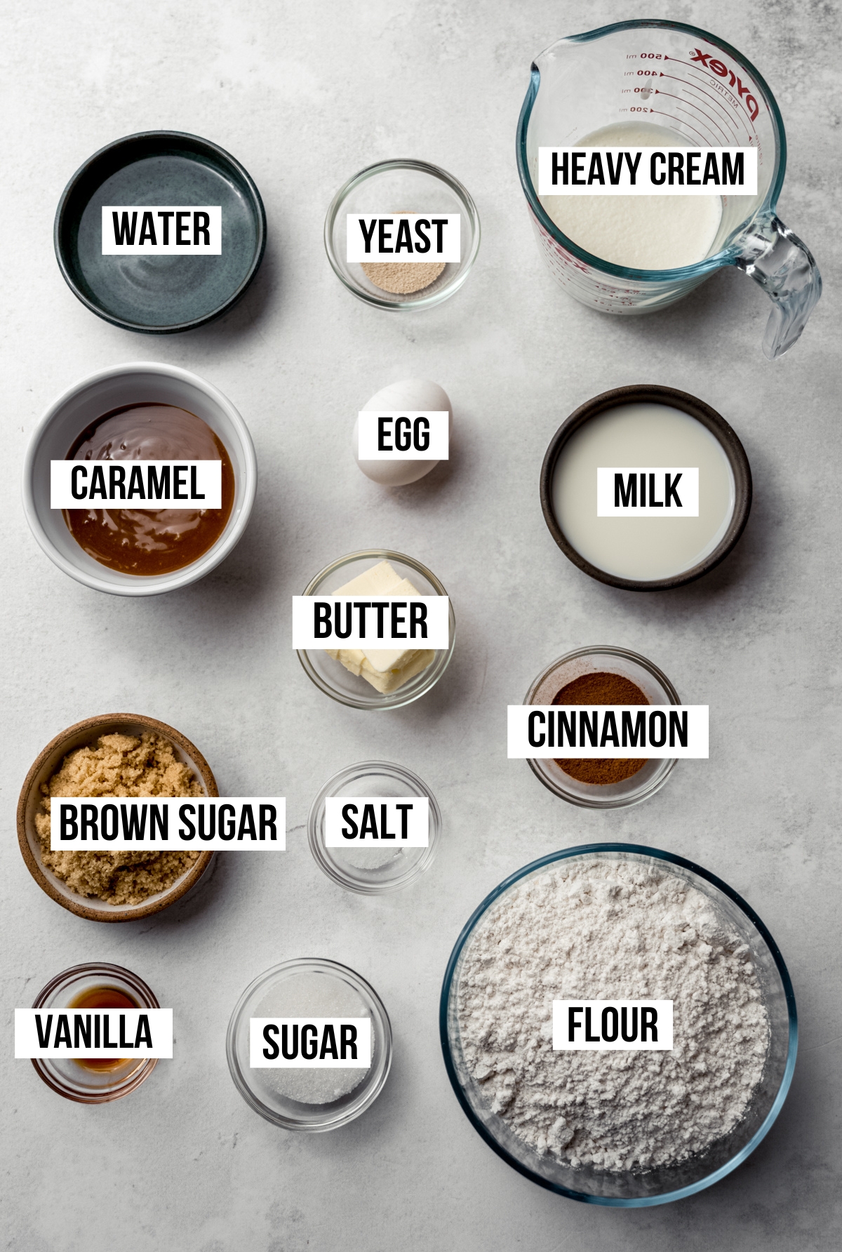 Aerial photo of ingredients to make caramel cinnamon rolls with text overlay labeling each ingredient.