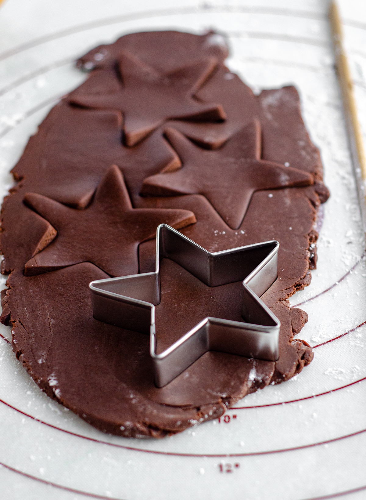 chocolate cut-out sugar cookie dough being cut into star shapes