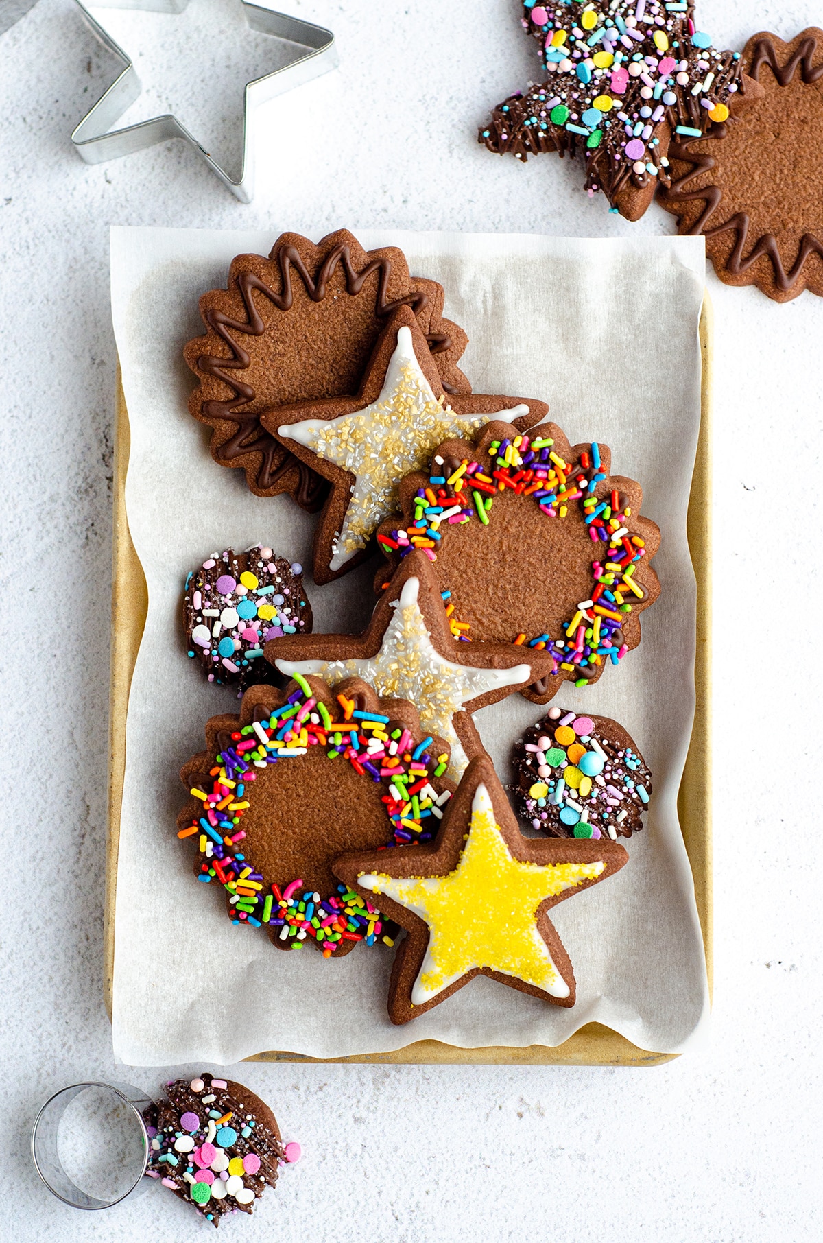 aerial photo of plate of chocolate cut-out sugar cookies decorated with icing and sprinkles