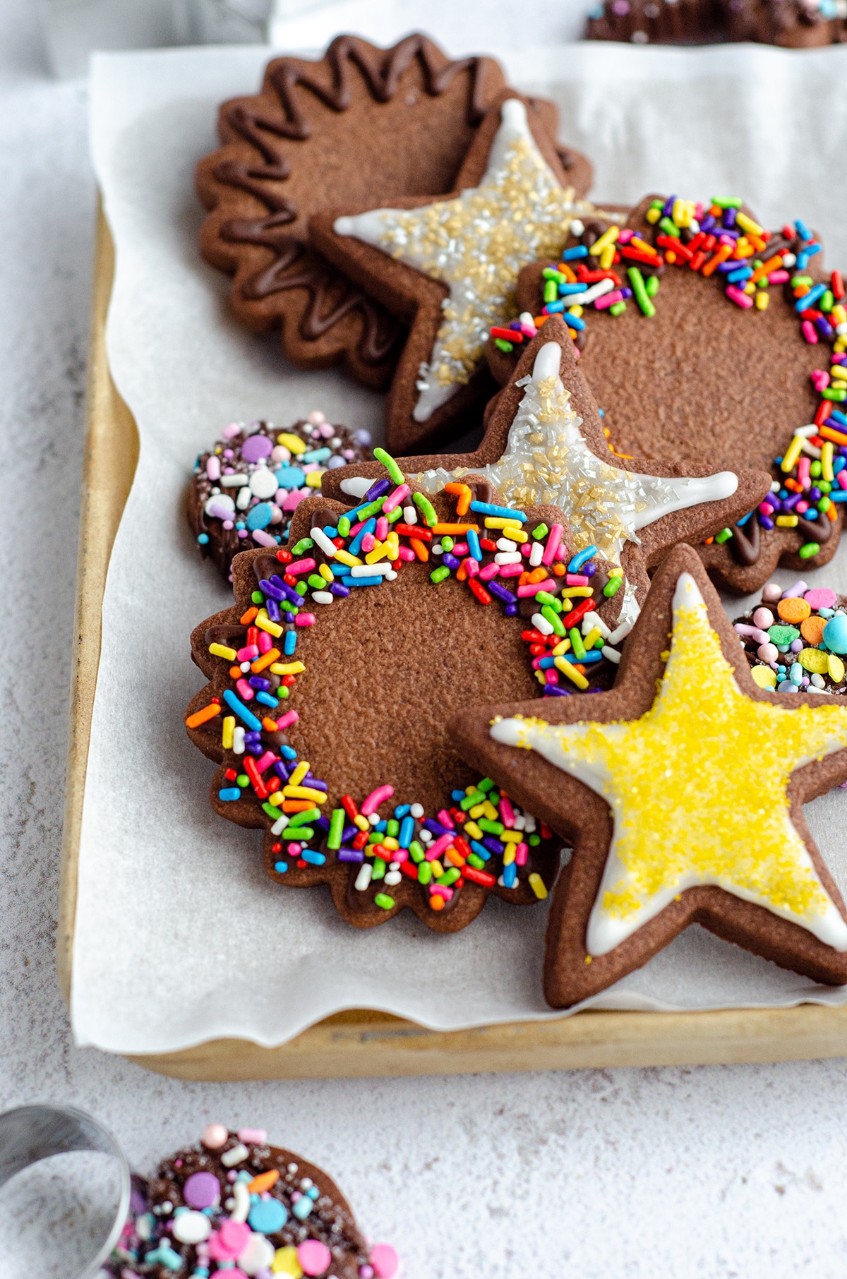 plate of chocolate cut-out sugar cookies decorated with icing and spirnkles