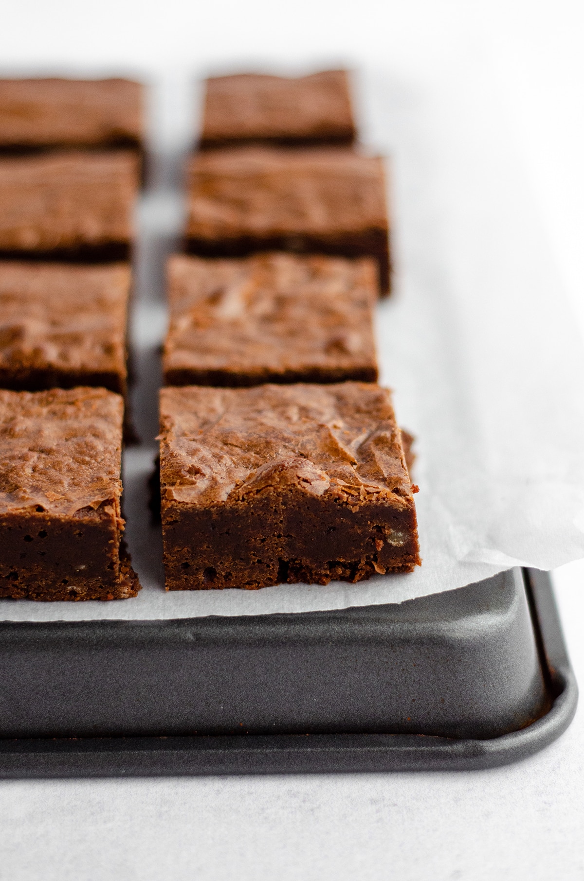 sliced brownies sitting on a surface with parchment paper