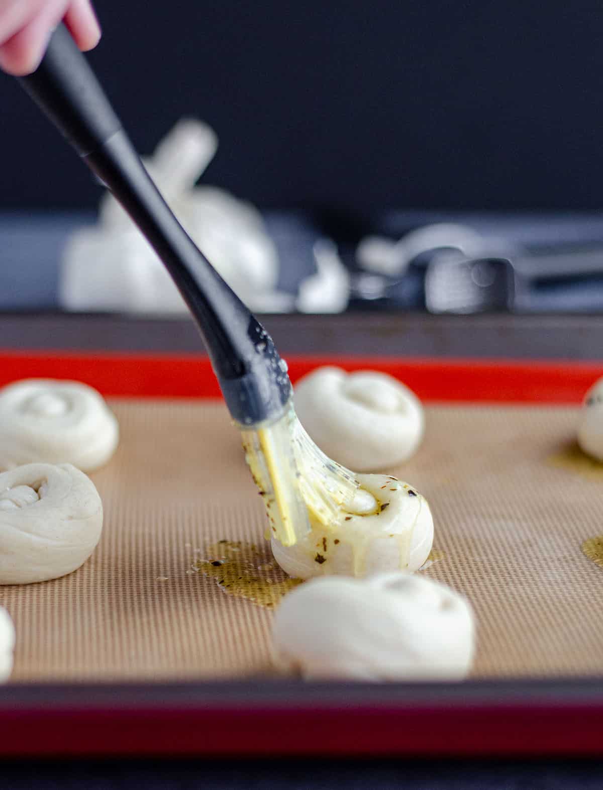 hand brushing garlic knots with garlic butter