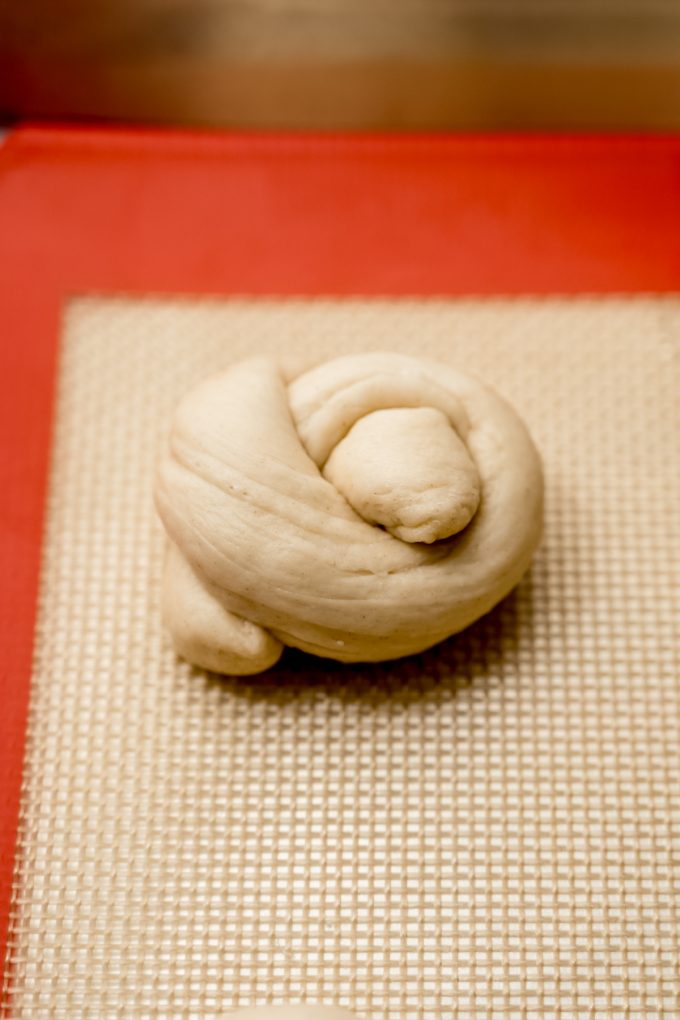 An unbaked garlic knot on a baking sheet.