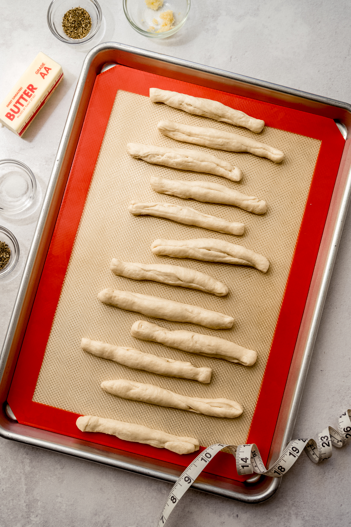 Logs of dough on a baking sheet that will be used to make garlic knots.