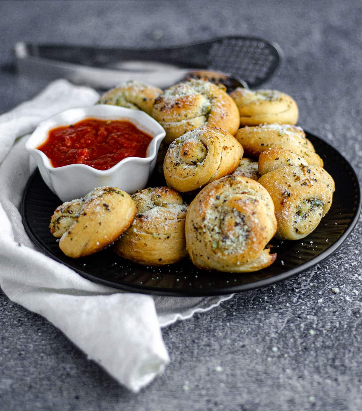 plate of homemade garlic knots with a bowl of marinara