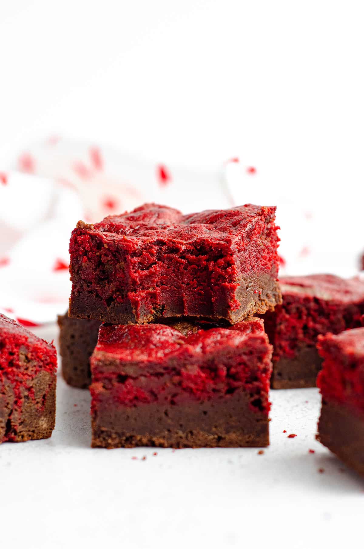 red velvet brownie with a bite taken out of it stacked on top of other red velvet brownies 