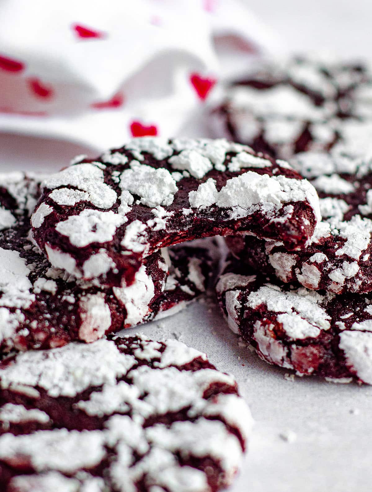 stack of red velvet crinkle cookies and one with a bite taken out of it