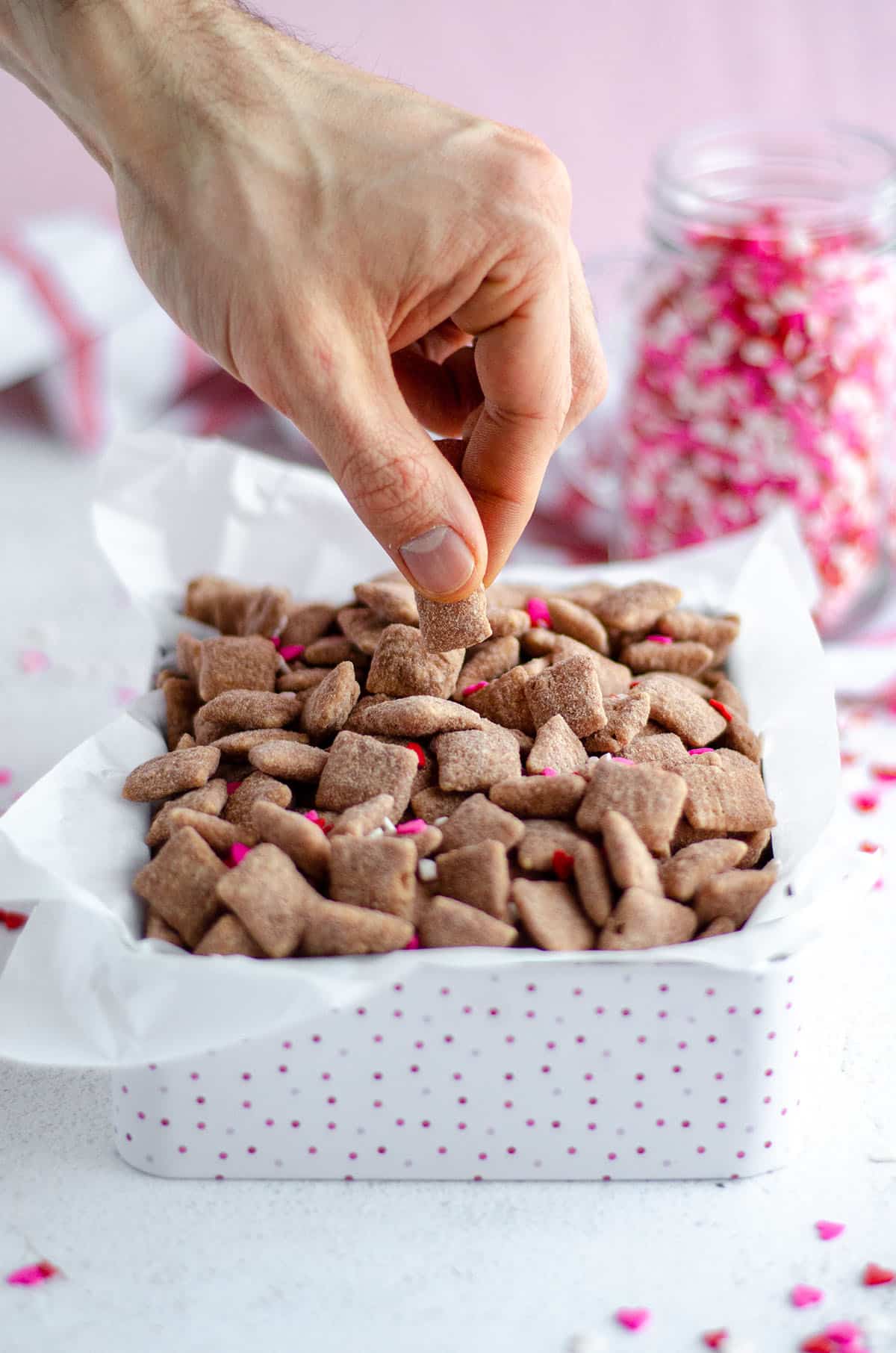 hand grabbing some red velvet puppy chow out of a treat box