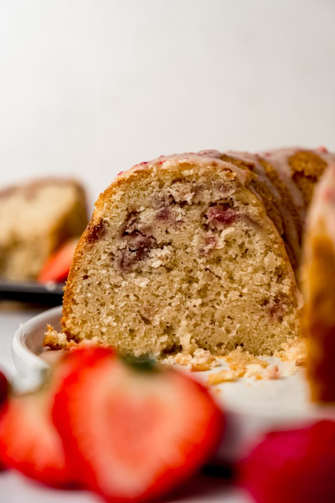 A strawberry Bundt cake with strawberry ganache on top sitting on a plate.