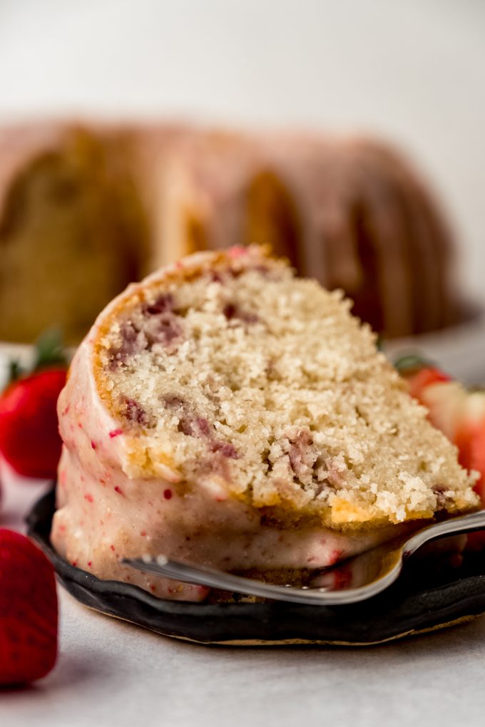 A slice of strawberry Bundt cake on a plate with a fork.