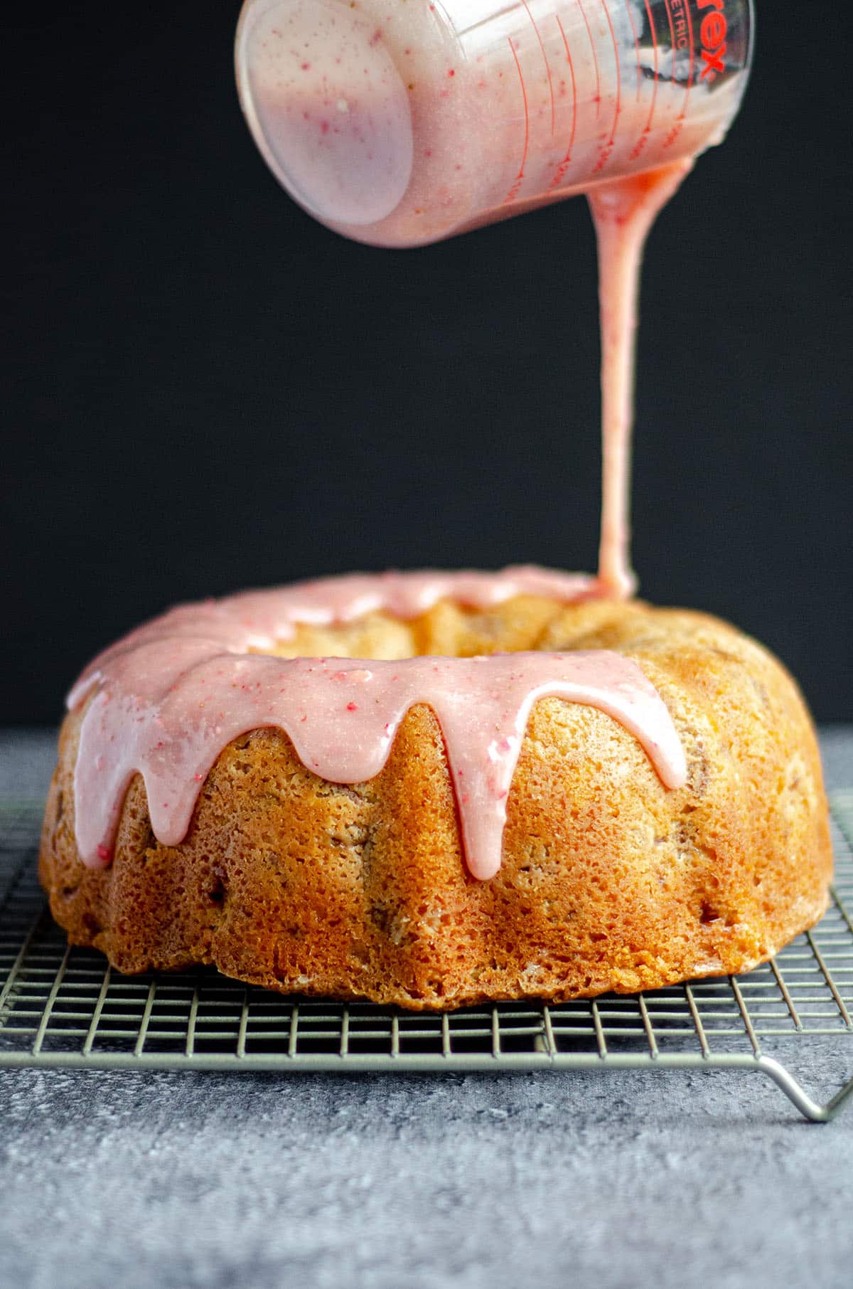 pouring strawberry ganache onto strawberry bundt cake