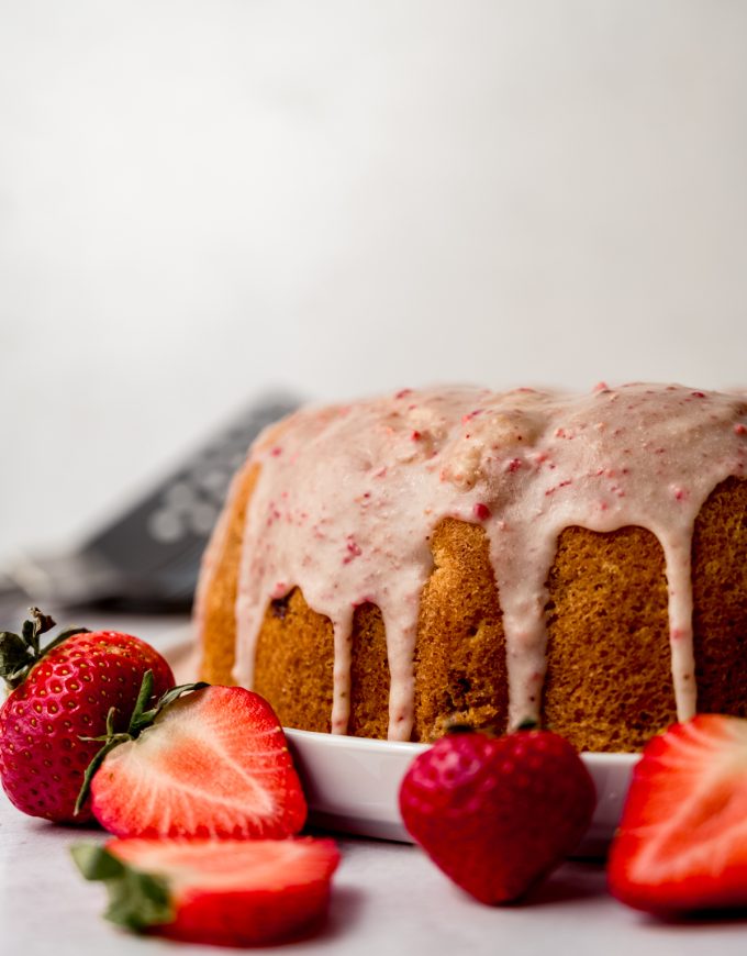 A strawberry Bundt cake with strawberry ganache on top sitting on a plate.