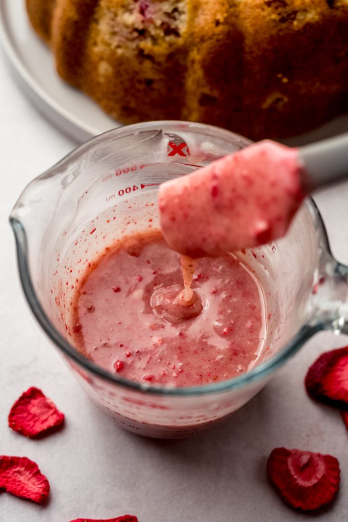 Someone is stirring freeze-dried strawberry powder into white chocolate ganache to make strawberry ganache.