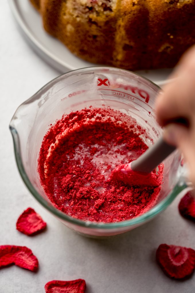 Someone is stirring freeze-dried strawberry powder into white chocolate ganache to make strawberry ganache.