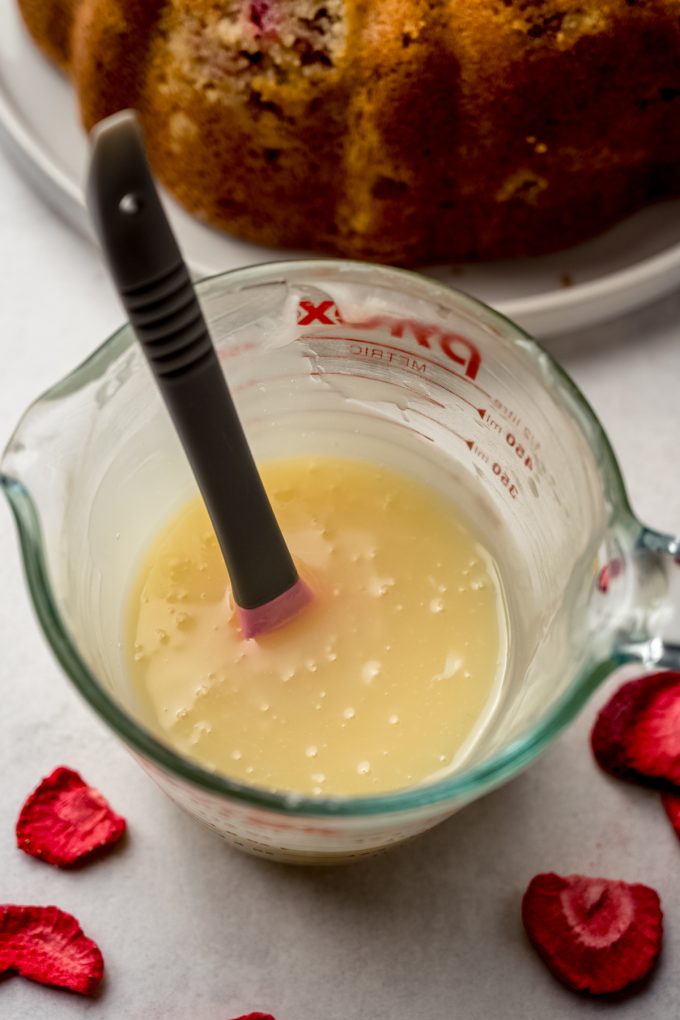 White chocolate chips and warm heavy cream in a glass measuring cup to make white chocolate ganache.