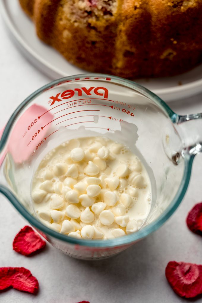White chocolate chips and warm heavy cream in a glass measuring cup to make white chocolate ganache.